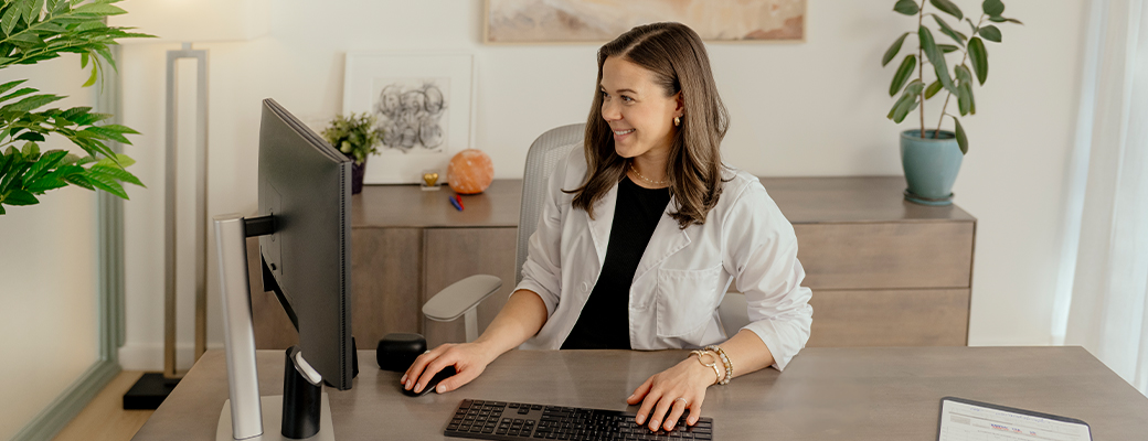 Image of female hearing care professional smiling and sitting at her desk